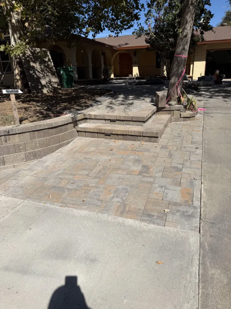 Paver patio with wide steps and block retaining wall at an arched stucco porch