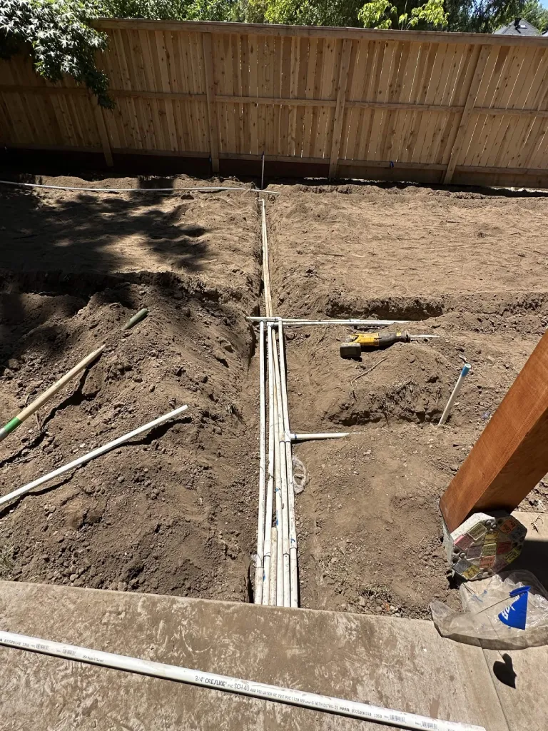 PVC sprinkler pipe grid trenched across a backyard ready for coverage