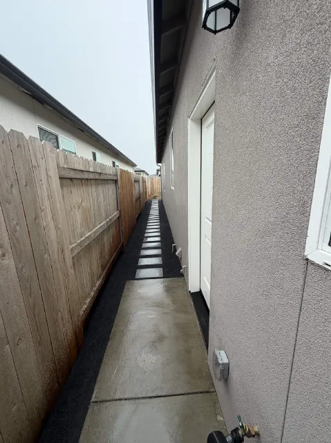Narrow side yard walkway with concrete and rock border