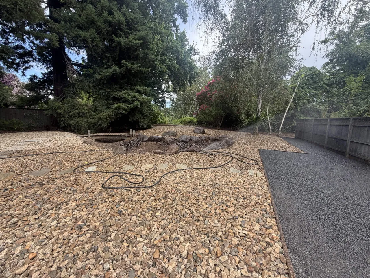 Backyard river rock ground cover with flagstone steppers and a crushed rock parking pad