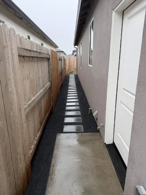 Side yard stepping stone path with black rock border