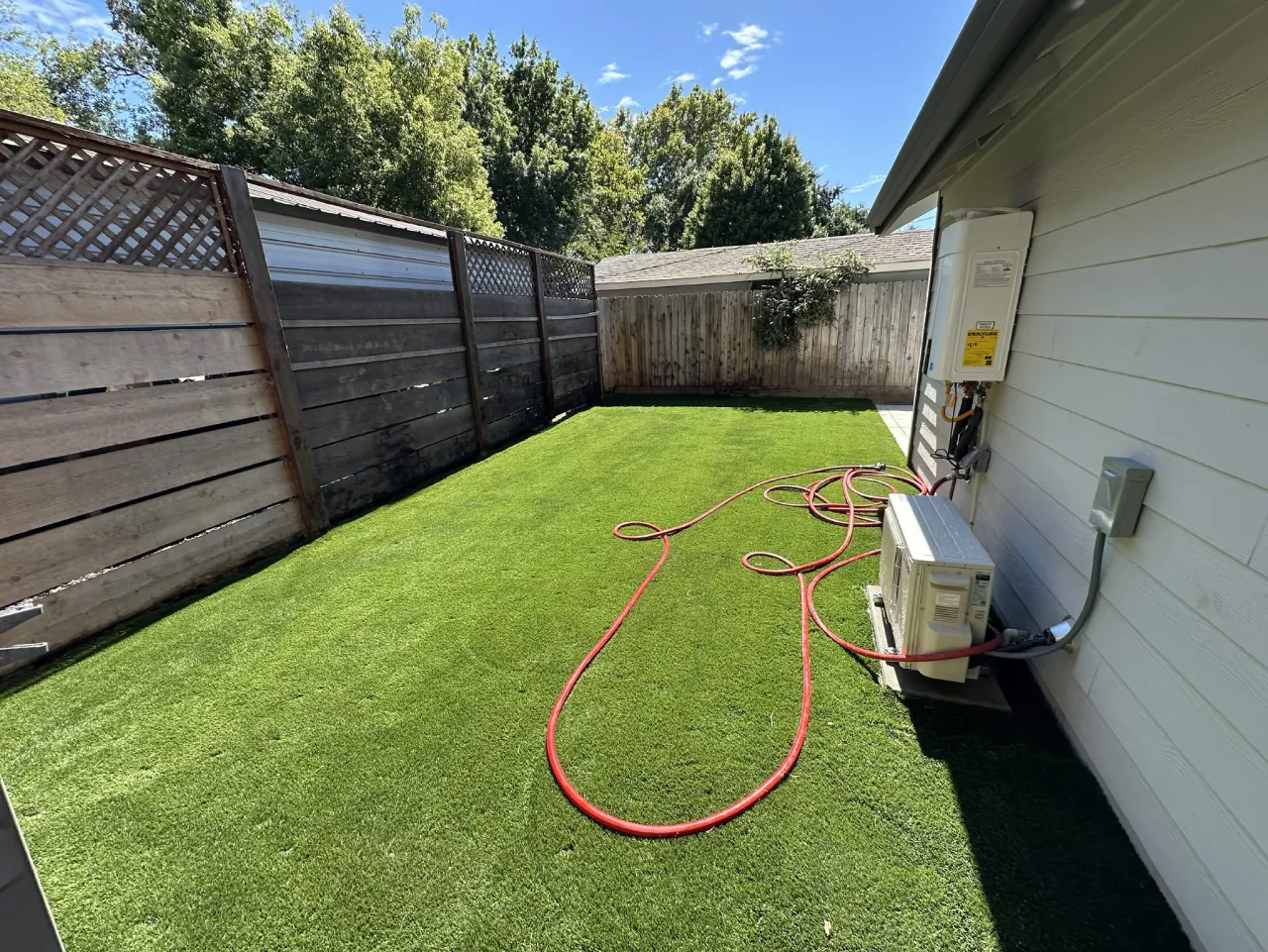Newly laid green lawn in a side yard with irrigation hose