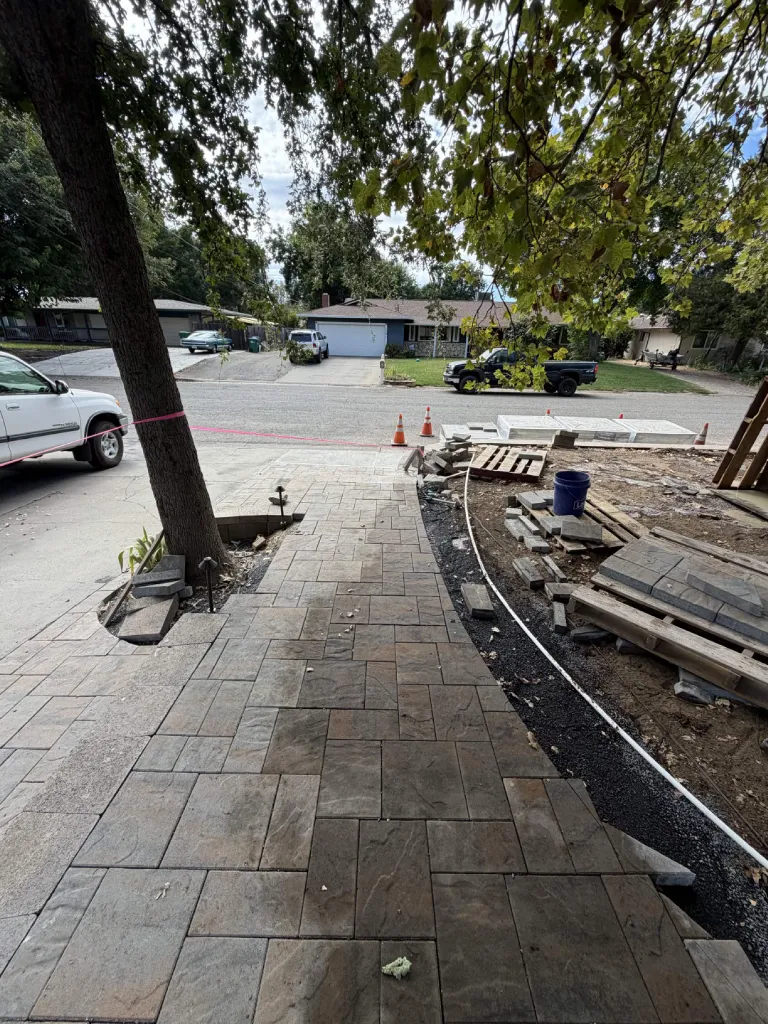 Wide paver walkway and driveway apron installed along a front yard
