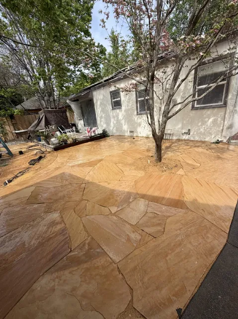 Flagstone patio installation around a backyard tree